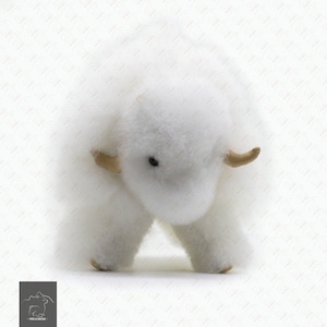 Może przedstawiać: Pluszowa biała zabawka przypominająca woła piżmowego z małymi czarnymi oczami i brązowymi rogami ze skóry.