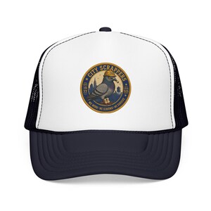 May include: A white and navy blue trucker hat featuring a circular patch on the front. The patch displays a pigeon wearing a yellow hard hat with the text CITY SCRAPPERS, EST 1977, LOCAL 515, and WE WORK WE SCAVENGE WE SURVIVE.