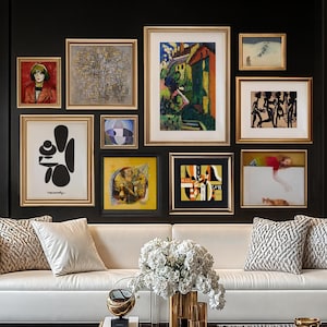 Puede incluir: Un sof&aacute; blanco con almohadas se encuentra frente a una pared negra con una pared de galer&iacute;a de obras de arte enmarcadas. Las obras de arte incluyen pinturas abstractas, paisajes y retratos. El sof&aacute; est&aacute; en una sala de estar con una mesa de caf&eacute; dorada y una mesa auxiliar dorada con una l&aacute;mpara.