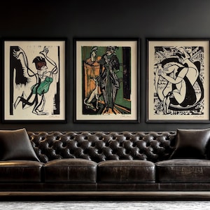 May include: Three black framed art prints with white matting hang above a black leather tufted sofa. The prints feature black and white stylized figures with green and orange accents.