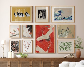 May include: A living room interior with a white couch, a wicker chair, and a wooden coffee table. The walls are decorated with framed artwork featuring Japanese-inspired designs, including cranes, waves, and flowers.