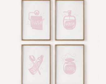 May include: Four framed pink bathroom art prints. Each print features a different bathroom-related icon: a roll of toilet paper with the word "FLUSH", a soap dispenser with "WASH", a toothbrush and toothpaste with "BRUSH", and a floss container with "FLOSS".