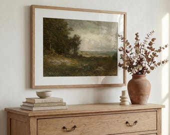 May include: A framed landscape painting featuring a dark, cloudy sky over a grassy field and trees, displayed above a light wood dresser. A terracotta vase filled with dried cotton stems sits next to a stack of three books.