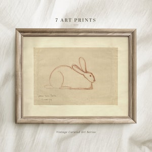 Op de afbeelding: Ingelijste kunstdruk met een roodbruine schets van een konijn op verouderd papier. De print zit in een licht houten frame. Tekst bovenaan luidt "7 ART PRINTS" en onderaan "Vintage Curated Art Series".