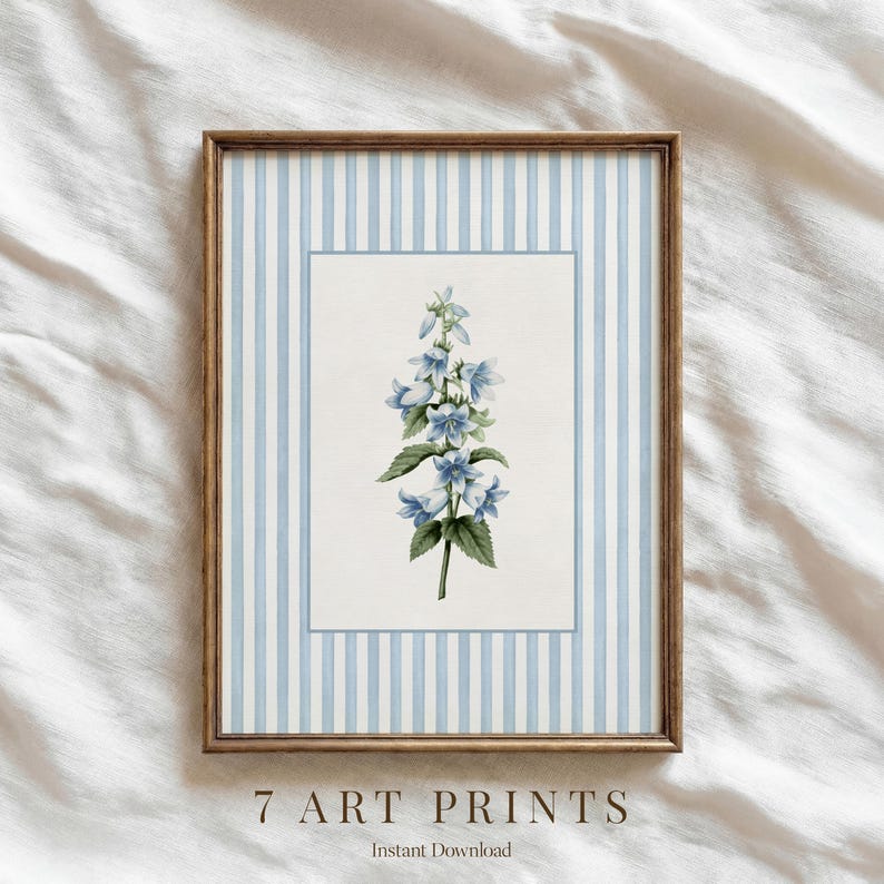 May include: Framed art print featuring a botanical illustration of blue flowers with green leaves. The artwork is set against a white background with a blue striped border and a wooden frame. The text "7 ART PRINTS" and "Instant Download" are at the bottom.