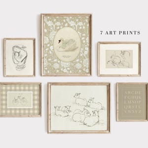 May include: Set of seven art prints in neutral colors with a variety of designs, including a swan, a bicycle, a rabbit, a group of lambs, and an alphabet. The prints are framed in light wood frames and arranged on a white wall.