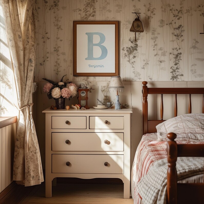 May include: A bedroom interior with a framed print displaying a blue letter "B" and the name "Benjamin". A cream chest of drawers holds a lamp and flowers. The room features floral wallpaper and a wooden bed frame. The scene evokes a cosy atmosphere.