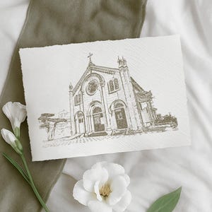 May include: A sepia-toned sketch of a church with a cross on top, set against a textured paper background. The church features arched doorways, a rose window, and detailed architectural elements. White flowers and a green fabric accent the scene.