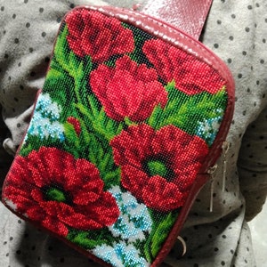 May include: A red leather crossbody bag with a beaded floral design featuring red poppies and green leaves. The bag has a zipper closure and a silver chain strap.