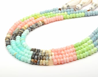 May include: A multi-strand necklace made of faceted gemstone beads in shades of blue, green, pink, and gray. The beads are strung on a clear cord and have a tassel at the end.