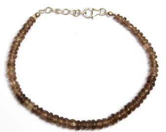 May include: A brown gemstone beaded bracelet with a silver clasp.