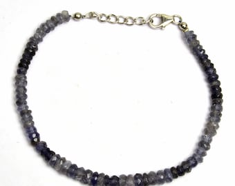 May include: A silver chain bracelet with a lobster clasp closure. The bracelet is made of small, faceted, dark blue gemstones.