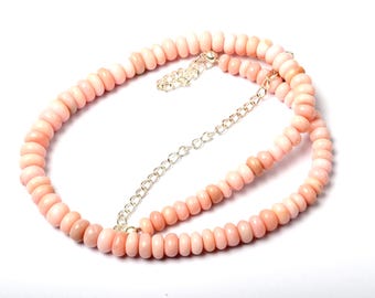 May include: A necklace composed of small, round, light pink beads. The beads are strung together with a silver-colored chain and clasp. The necklace is displayed on a white background.