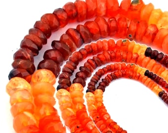 May include: A collection of faceted gemstone beads arranged in multiple strands. The beads display a gradient of warm colors, ranging from deep dark red and brownish-red to vibrant orange, bright tangerine, and pale yellow-orange hues.