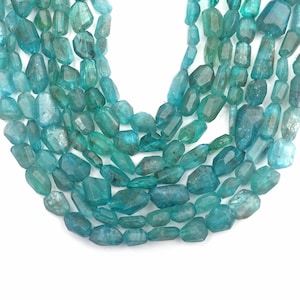 May include: A strand of teal blue gemstone beads, faceted and with a slightly irregular shape. The beads are strung together to form a necklace or bracelet.
