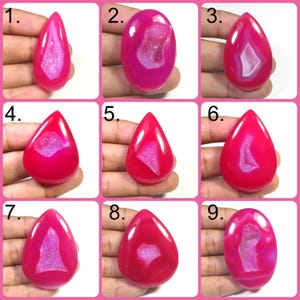 May include: Nine polished, vibrant pink agate gemstones with varying shapes and internal crystal formations. Each stone is held in a hand, showcasing the unique patterns and textures of the natural materials. Ideal for jewelry making or collecting.
