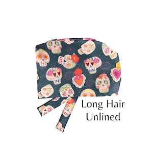 May include: A dark blue surgical scrub hat with a colorful sugar skull pattern. The hat is designed for long hair and is unlined.  Long Hair Unlined