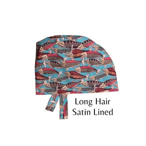 May include: A blue and red patterned surgical cap with a long tie. The cap is made of fabric with a satin lining. The pattern features stylized fish.