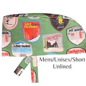 May include: Green ski cap with colorful patches featuring ski resort logos like "SKI COLORADO", "IDAHO", and "MT BAKER". The cap is labeled "Mens/Unisex/Short Unlined".