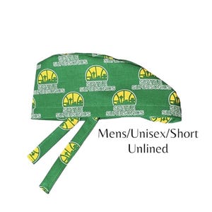 May include: Green surgical scrub hat with a repeating pattern of the Seattle SuperSonics logo. The hat has two ties and the text "Mens/Unisex/Short Unlined" is printed below the hat.