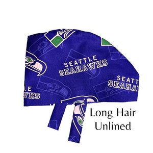 May include: A blue surgical scrub hat with a Seattle Seahawks logo pattern. The hat has a long tie and the text "Long Hair Unlined" is printed on the bottom.