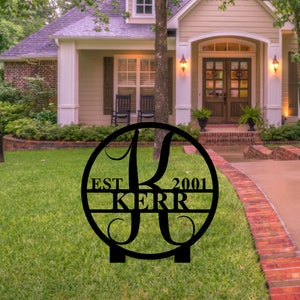 May include: Black metal yard sign with a circle design featuring the letter K, the text "EST 2001" and the name "KERR".