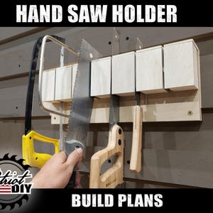 May include: A wooden hand saw holder with five slots for storing hand saws. The holder is mounted on a wall and has a light wood finish. The text "HAND SAW HOLDER" is printed in black at the top of the image. The text "BUILD PLANS" is printed in black at the bottom of the image.