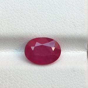 Puede incluir: Una gema ovalada de color rosa vibrante con un corte facetado.