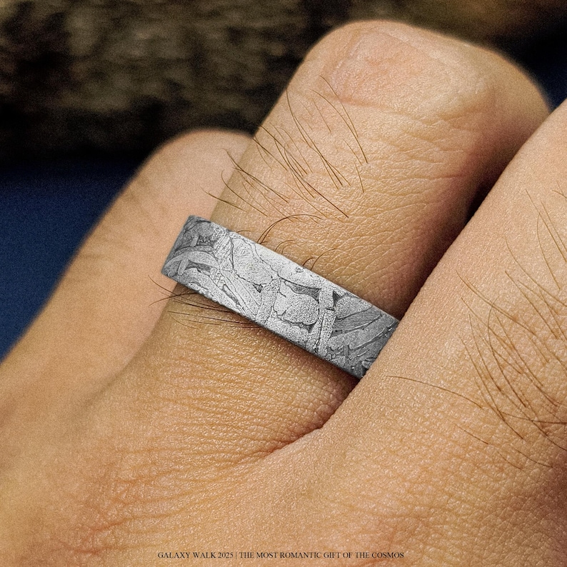 K&ouml;nnte beinhalten: Nahaufnahme eines silbernen Rings mit einem einzigartigen, strukturierten Muster. Der Ring wird an einem Finger getragen und zeigt sein aufwendiges Design. Der Text unten lautet "GALAXY WALK 2025 | THE MOST ROMANTIC GIFT OF THE COSMOS."