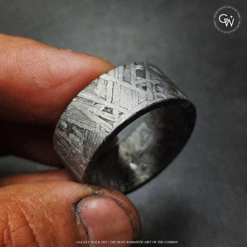 May include: A close-up shot of a silver-toned ring with a distinctive, textured pattern. The ring has a wide band and a dark interior. The text at the bottom reads "GALAXY WALK 2025 | THE MOST ROMANTIC GIFT OF THE COSMOS."