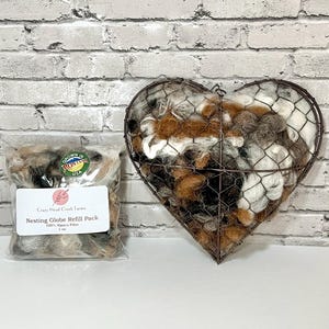 May include: A bag of brown, white, and black alpaca fiber refill for a nesting globe. The bag has a label that says "Crazy Head Creek Farms" and "Nesting Globe Refill Pack 100% Alpaca Fiber 1 oz". The fiber is also shown in a wire heart-shaped container.