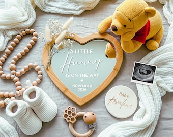 May include: A baby announcement featuring a heart-shaped mirror with the text "A Little Hunny Is On The Way" and the date November 2026. Includes a Winnie the Pooh plush, baby booties, and a sonogram.