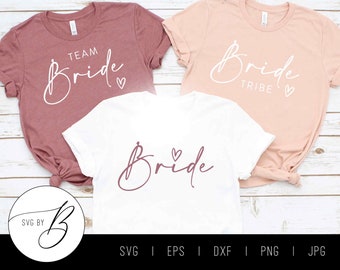 May include: Three white t-shirts with the text "Bride", "Team Bride", and "Bride Tribe" in a cursive font. The shirts are on a white wooden background. The text is in a white font with a pink heart.