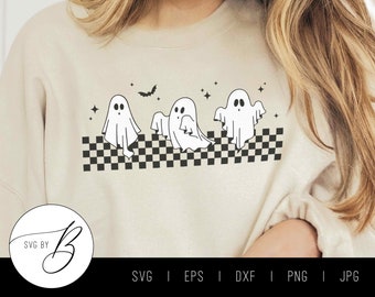 May include: A white sweatshirt with a black and white checkered pattern and three ghosts with black eyes. The ghosts are in a row and there is a bat above them. The text "SVG BY" is in a circle on the bottom left of the image.