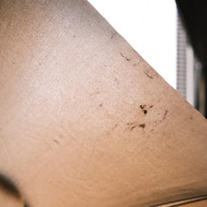 Puede incluir: Primer plano de una tela beige con manchas oscuras y un contorno negro. La tela est&aacute; tensa, creando una forma triangular. La textura parece ligeramente &aacute;spera, con imperfecciones visibles.