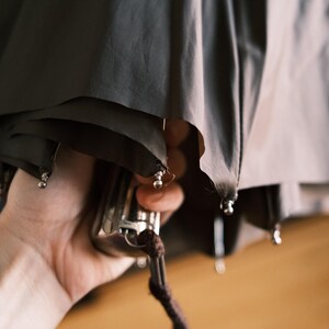 Puede incluir: Una taza de cer&aacute;mica blanca con un asa negra y el texto "But First, Coffee" en negrita negra. La taza est&aacute; llena de un l&iacute;quido oscuro, probablemente caf&eacute;, y se encuentra sobre una superficie blanca.