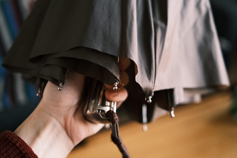 Puede incluir: Una taza de cer&aacute;mica blanca con un asa negra y el texto "But First, Coffee" en negrita negra. La taza est&aacute; llena de un l&iacute;quido oscuro, probablemente caf&eacute;, y se encuentra sobre una superficie blanca.