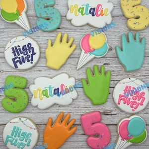 May include: A set of 12 decorated sugar cookies featuring a handprint, balloons, the number 5, and the name Natalie. The cookies are decorated with colorful icing and sprinkles.