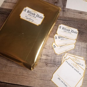 May include: A gold-wrapped book with a label that reads "A Blind Date with a book" and the word "Mystery". There are several blank cards with the same label, and one card with the text "I'd describe myself as..." and "My red flags:"