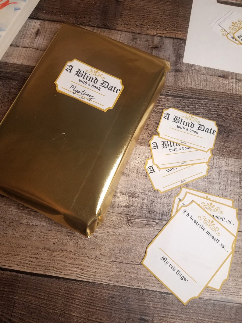 May include: A gold-wrapped book with a label that reads "A Blind Date with a book" and the word "Mystery". There are several blank cards with the same label, and one card with the text "I'd describe myself as..." and "My red flags:"