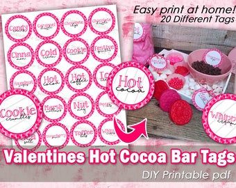 May include: A collection of Valentine's Day-themed hot cocoa bar tags. The tags are round with a pink heart border and feature various flavors like "Hot Cocoa," "Cookie crumbles," and "Whipped cream." The image also includes a bowl of chocolate chips and marshmallows.