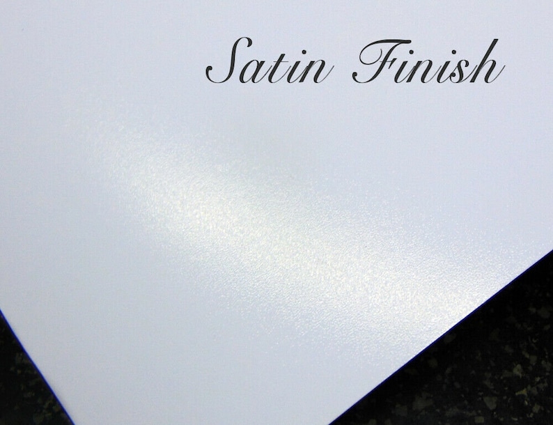May include: A close-up of a white surface with a subtle, textured satin finish. The surface has a slight sheen and a smooth, even texture. The text "Satin Finish" is written in black cursive lettering at the top of the image.