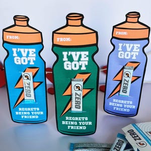 May include: Three Valentine's Day cards in the shape of water bottles, featuring Gatorade branding. The cards are blue, green, and purple, with the text "I'VE GOT" and "REGRETS BEING YOUR FRIEND". Each card includes a Gatorade Zero sachet.