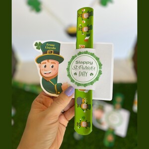 May include: A green and white slap bracelet with a cartoon leprechaun design. The bracelet has the text "Slappy St. Patrick's Day" on it.
