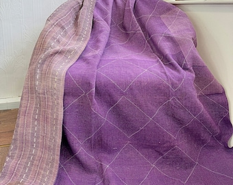 May include: A purple quilted throw blanket with a diamond pattern. The blanket is folded and draped over a chair.