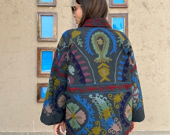 May include: A dark green jacket with colorful embroidery featuring floral and paisley patterns. The jacket has a collar and long sleeves.