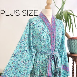 May include: A turquoise blue silk robe with a paisley print and pink trim. The robe has a tie belt and long sleeves. The text "PLUS SIZE" is visible in the image.