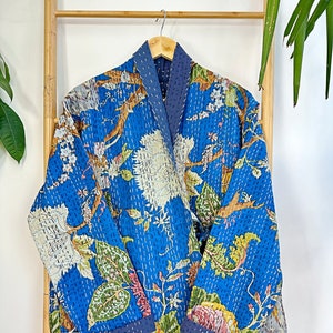 May include: A blue quilted jacket with a floral print. The jacket has a long sleeve and a collar. The jacket is made of cotton and is lined with a blue fabric.