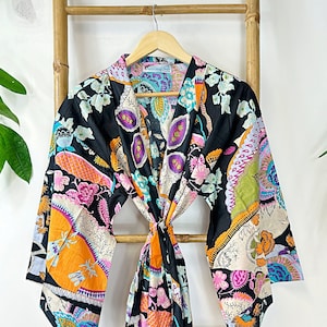 Może przedstawiać: Czarny kimon z kolorowym wzorem paisley. Kimono ma długie rękawy i pasek do wiązania. Wzór zawiera kolory pomarańczowy, różowy, niebieski i zielony.