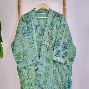 May include: A green quilted robe with a floral print and contrasting white stitching. The robe has a long, open front and a wide collar.